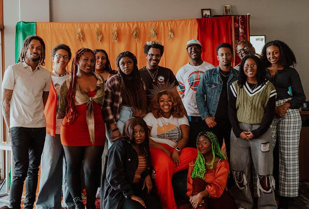 The Black Student Coalition gathered together in front of a colorful green, orange, and red backdrop